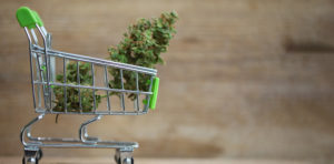 Tiny shopping cart with green handles holding cannabis